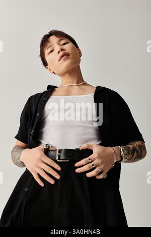 A young, stylish Asian man stands confidently in a serene setting. Stock Photo