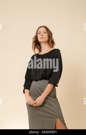 Female model wearing high waist pencil skirt and black silk blouse, studio shot Stock Photo