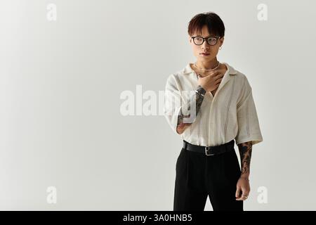 A young, handsome Asian man confidently poses in a minimal studio, showcasing his style. Stock Photo