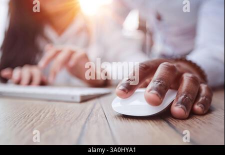 black man holding a computer mouse on the table, close-up Stock Photo