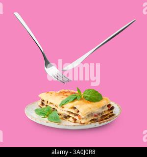 Cutlery in air over plate with tasty lasagna on violet pink background Stock Photo