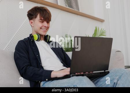 Happy young entrepreneur feeling excited about new project while working on laptop at home. Stock Photo