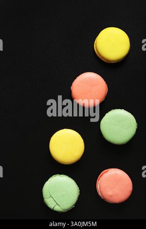 Bright French macarons on a black background, top view. Assortment of multi-colored macarons with different flavors. Delicious pastries, flat lay. Foo Stock Photo