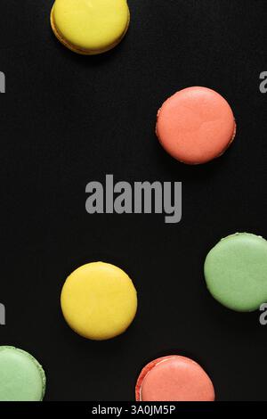 Bright French macarons on a black background, top view. Assortment of multi-colored macarons with different flavors. Delicious pastries, flat lay. Foo Stock Photo