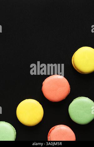 Bright French macarons on a black background, top view. Assortment of multi-colored macarons with different flavors. Delicious pastries, flat lay. Foo Stock Photo