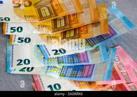 Scattered 10, 20 and 50 variegated euro banknotes on a gray background, low wage income concept Stock Photo
