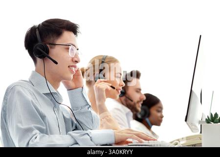 Diverse team of call centre operators working with computers at modern open space office Stock Photo