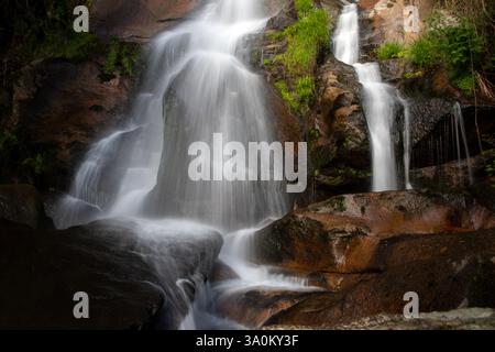 Serene Waterfall Cascading Over Rocks in Nature Stock Photo