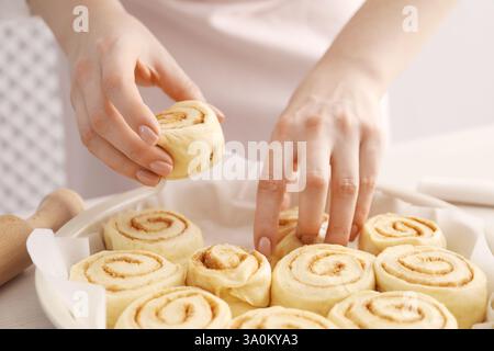 Woman making cinnamon rolls at table, closeup Stock Photo