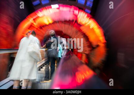 Visitors on an Escalator with Blurred Motion with Fiery Light Tunnel in Natural History Museum, London Stock Photo