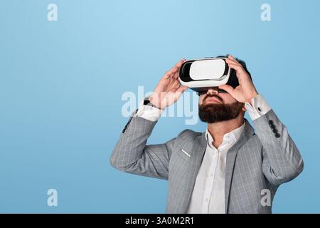 Businessman in virtual reality headset exploring cyberspace on blue background Stock Photo