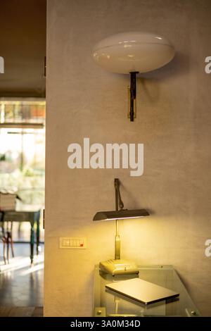 A stylish home workspace featuring a vintage wall sconce and a sleek desk lamp casting warm light. The minimalist aesthetic and neutral tones create a cozy yet productive atmosphere Stock Photo