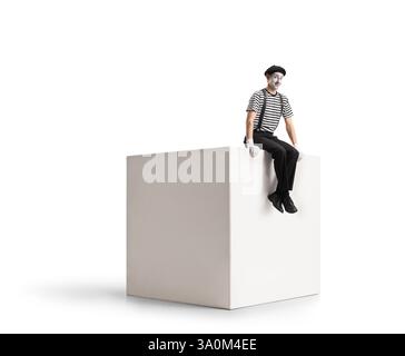 Mime sitting on a white cube isolated on white background Stock Photo
