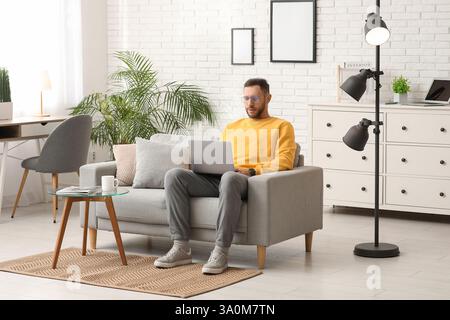 Young man using laptop on sofa at home Stock Photo