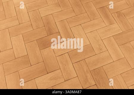 Old wooden parquet floor showcasing an intricate geometric pattern with warm tones. Background photo texture Stock Photo