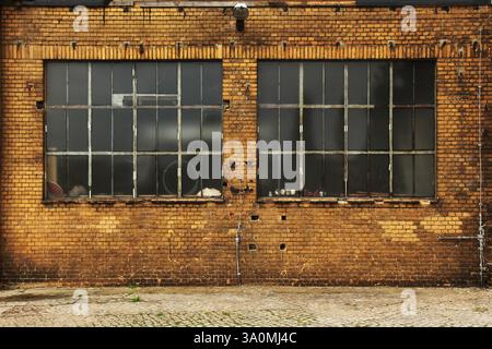 a colorful brick wall of an old building with two windows Stock Photo