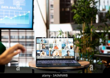 Employee having online discussion with coworkers in video call meeting, working from stylish office. Staff member in video conference over the internet with teleworking colleagues Stock Photo