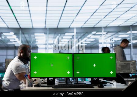 Multi monitor isolated screen computers in data center used by IT employees for supervising server rows in computer network security data center, overseeing supercomputers Stock Photo