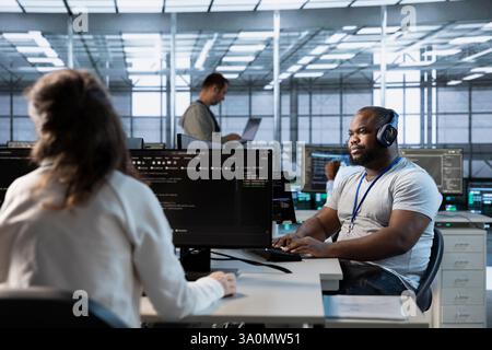 Engineer in data center coordinating deployment of server architecture, improving data processing speed in client workload capacity. Server room expert configuring and testing hardware Stock Photo