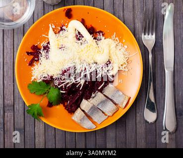 Sliced herring with grated beetroot and cheese served on table Stock Photo