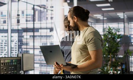 Programmer and colleague conducting experiments and tests to optimize machine learning models for performance and accuracy. IT staff members in office analyzing and interpreting complex data, camera A Stock Photo