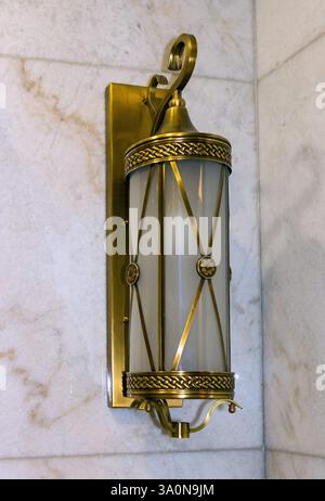 Old vintage empty lantern with metal frame and glass cover hanging on a wall Stock Photo