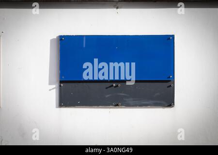 A rectangular blue plaque hangs on the exterior wall of an office building in Germany. Its vibrant color contrasts with the neutral background, offeri Stock Photo
