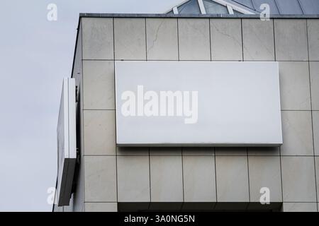 An empty rectangular white sign affixed to the facade of an office building in Germany. This blank display provides ample space for potential branding Stock Photo