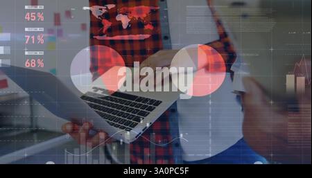 Image of data processing and diagrams over diverse colleagues using laptop and tablet Stock Photo