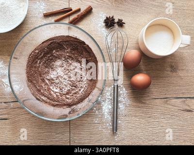 Making spicy chocolate dough. Ingredients for baking the sponge cake are laid out on a wooden table. View from above. Stock Photo