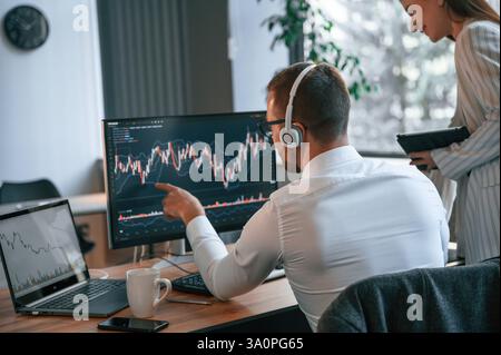 Two office workers are analyzing graphs that on the computer screen. Stock Photo