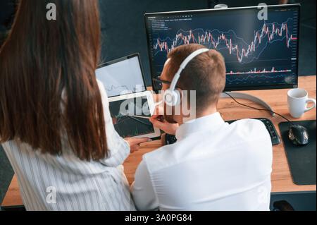 Two office workers are analyzing graphs that on the computer screen. Stock Photo