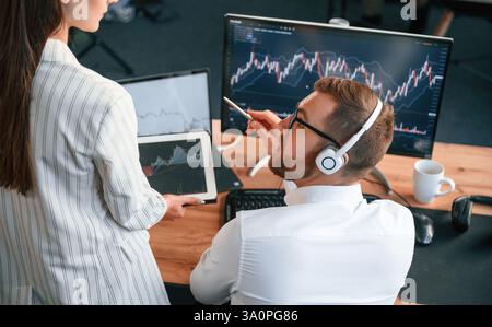 Two office workers are analyzing graphs that on the computer screen. Stock Photo