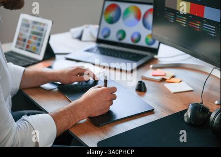With graphic tablet. Close up view of designer's hands. Man in formal clothes is working in the modern office. Using computer. Stock Photo