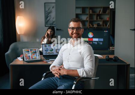Positive man is smiling. Two employees are working together in the modern office. Stock Photo