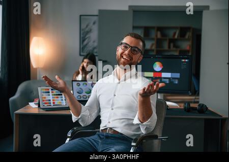 Positive man is smiling. Two employees are working together in the modern office. Stock Photo
