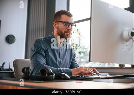 Typing on the keyboard. Man in formal clothes is working in the modern office. Using computer. Stock Photo