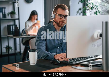 Man is using computer. Two employees are working together in the modern office. Stock Photo