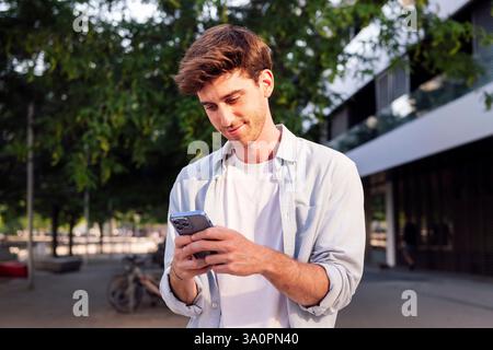 man using cell phone while walking down the street Stock Photo