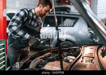 Car details. Repairing the vehicle. Man in uniform is working in the auto salon. Stock Photo