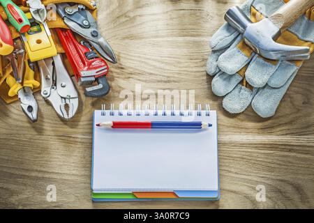 Construction tooling tool belt protective gloves claw hammer notebook pencil Stock Photo