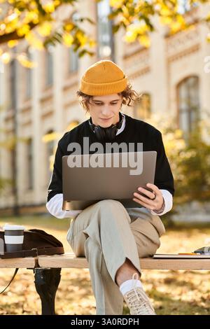 Handsome young man with stylish attire focused on his laptop while enjoying nature outside. Stock Photo