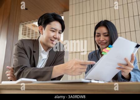 Effective teamwork. Two individuals collaborating on project details in a contemporary setting. Stock Photo