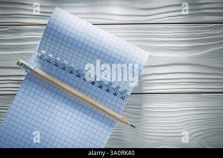 Checked spiral blank notepad pencil on white wooden board Stock Photo