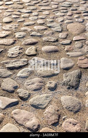 road made of cobblestones, an old-style pavement made of cobblestones of different sizes Stock Photo