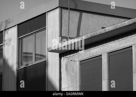 Sunlight casting shadows on a concrete building with geometric shapes, showcasing modernist architectural style in monochrome Stock Photo