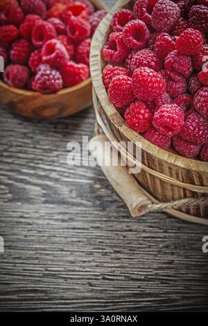 Bowl and bucket with red raspberries on wooden board Stock Photo