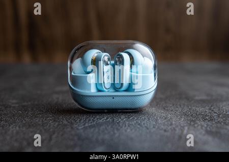 Wireless Blue Earbuds with Charging Case on Dark Textured Surface Stock Photo