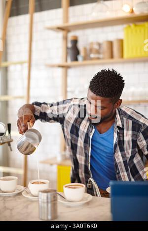 Barista, man and coffee preparation with milk in cafe for customer order, cappuccino beverage and pouring. Hospitality industry, latte process and Stock Photo