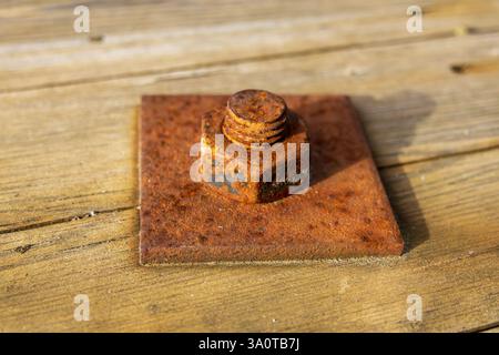 Close-up of a rusted screw and nut with a large square washer on weathered wooden planks, highlighting aged textures and natural patterns. Perfect fo Stock Photo